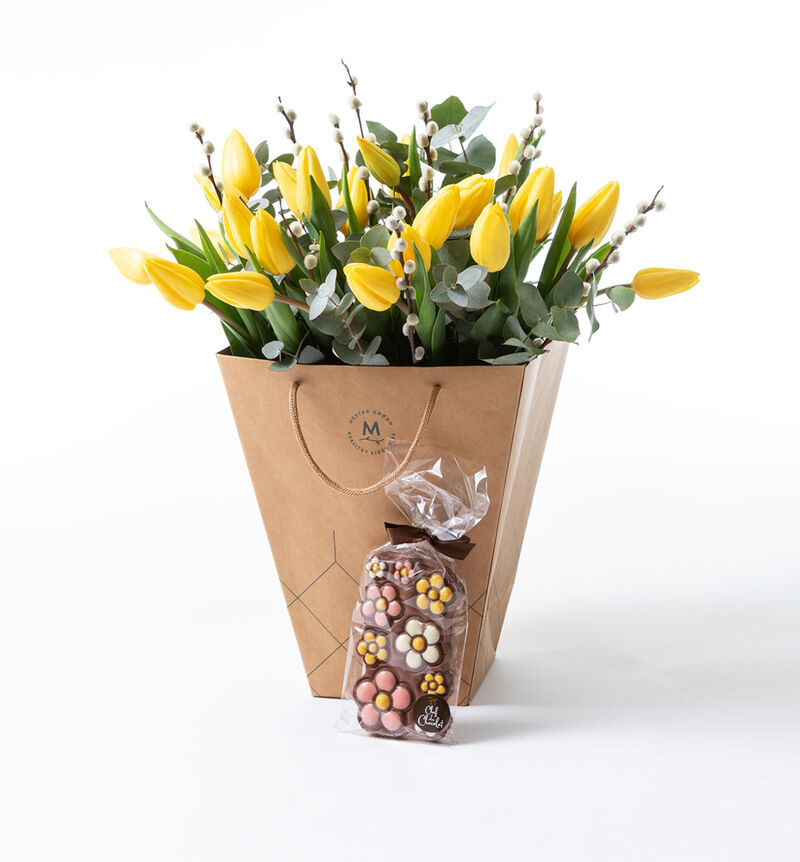 Yellow tulip bouquet in gift bag with chocolate